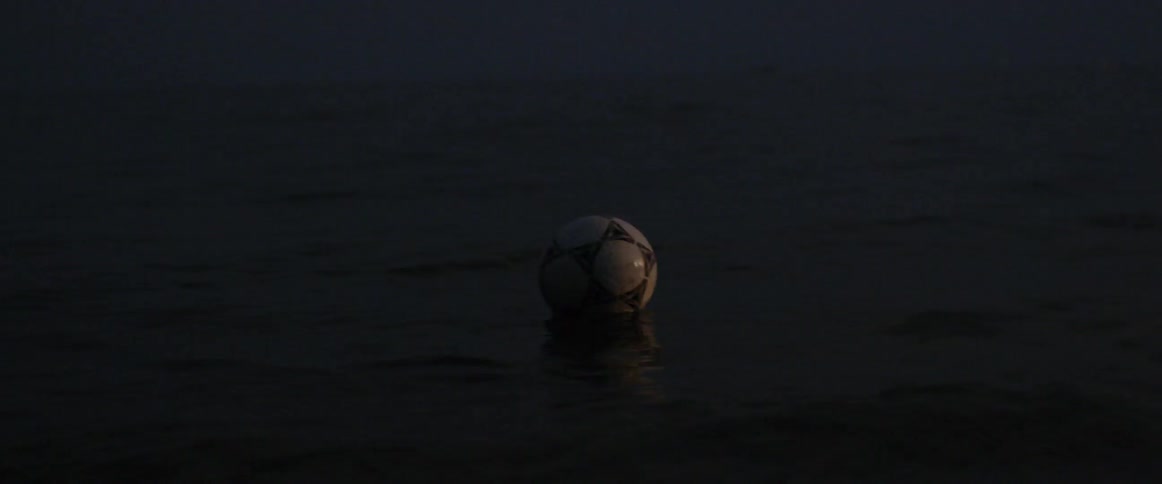 A soccer ball floats on top of an open body of calm water