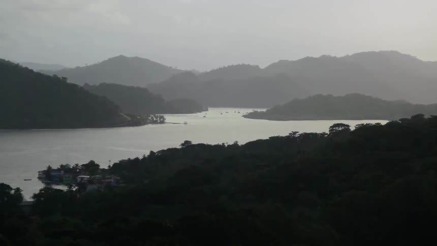 A mountain range that is covered in trees has a large river passing below it