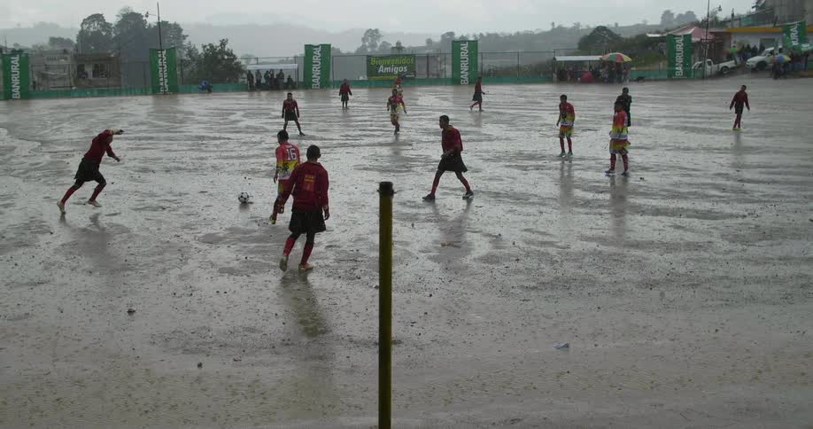 Group of men playing soccer outdoors in the rain