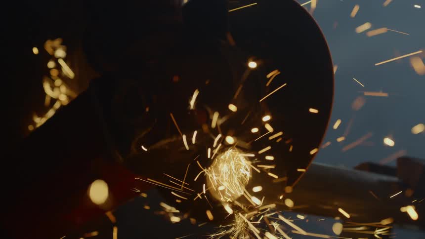 Sparks fly around a person using a saw