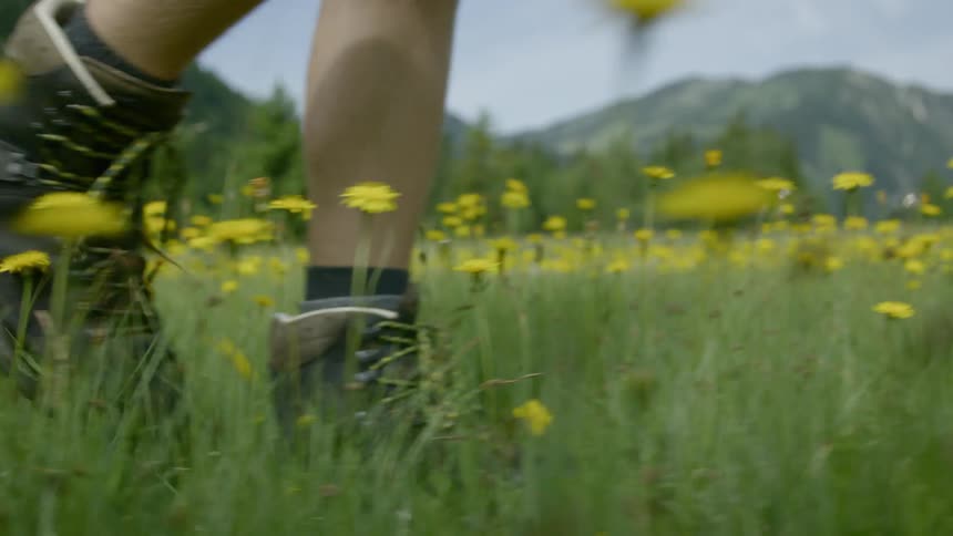 Man wearing boots walks on the green grass in the field