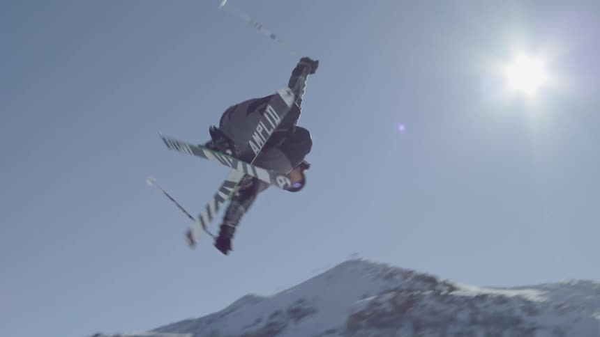 A skier launches off a ski ramp and twists multiple times in the air before landing perfectly on the snowy slope
