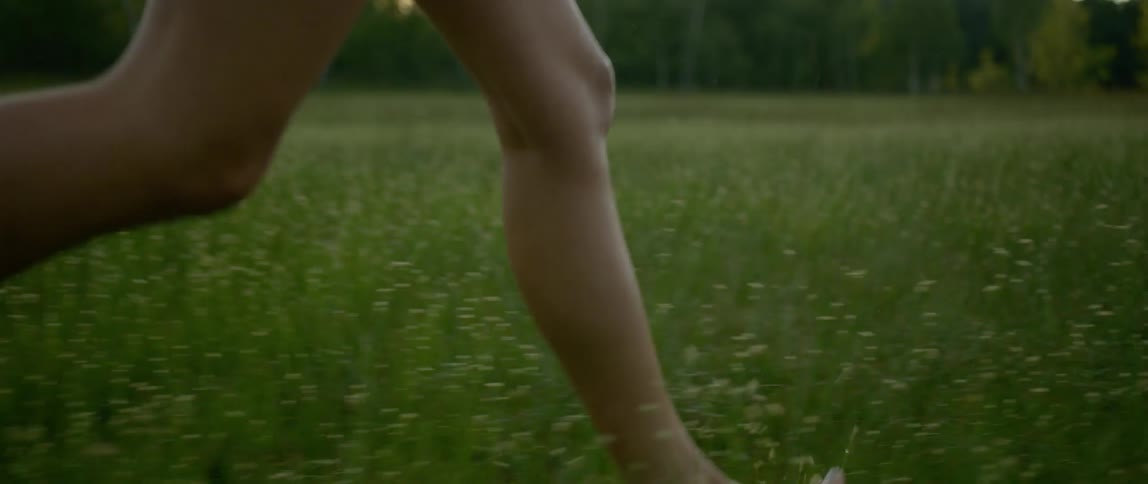 Legs of woman running through a grassy field outdoors