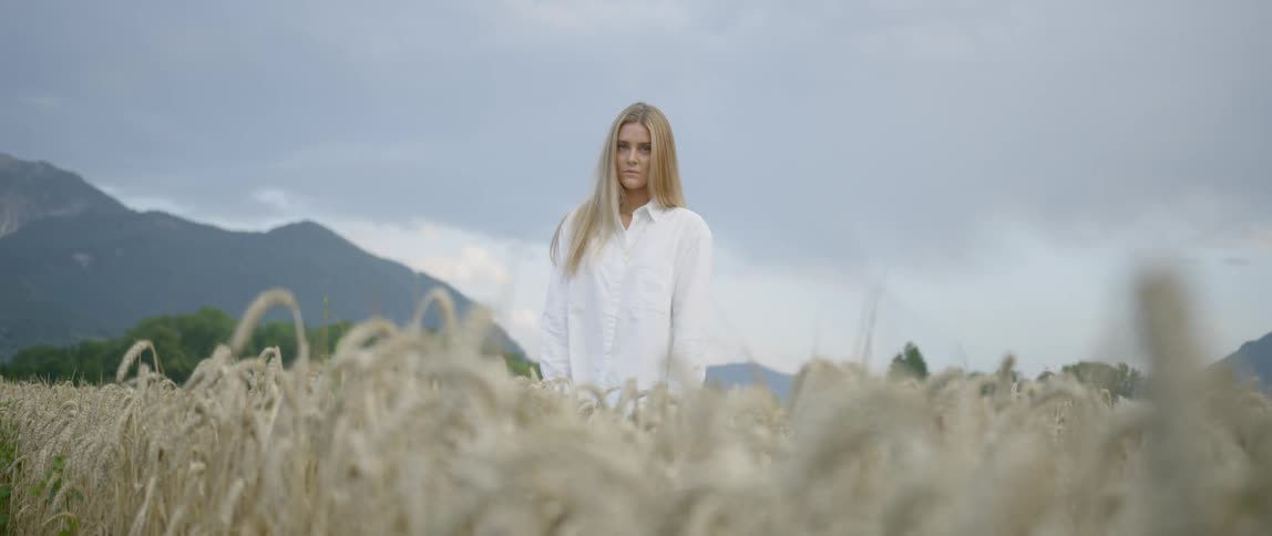 Sad woman standing in the middle of a wheat field