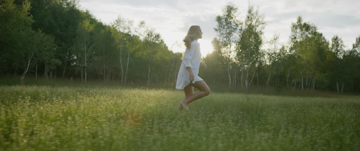 A woman with white shirt running in the grass field