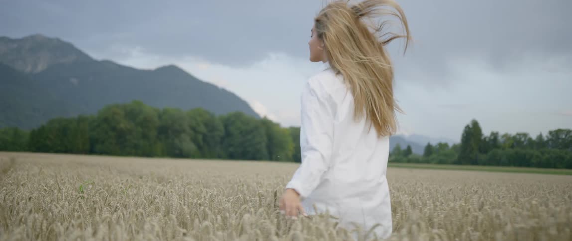 A woman runs through a field wearing a long shirt