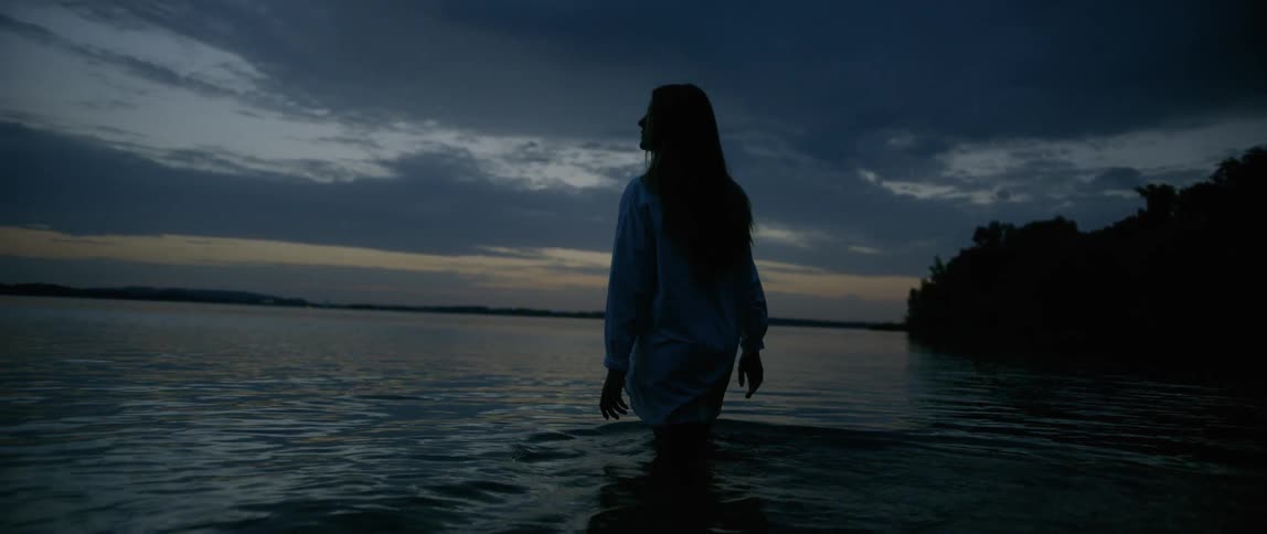 A silhouette portrait of a female walks toward the sea