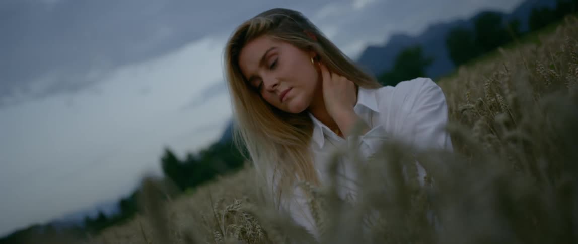 A portrait of a female under cloudy sky