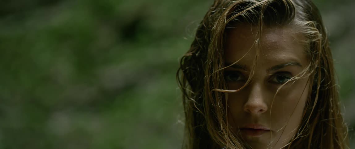 A blonde woman staring at the camera at the forest