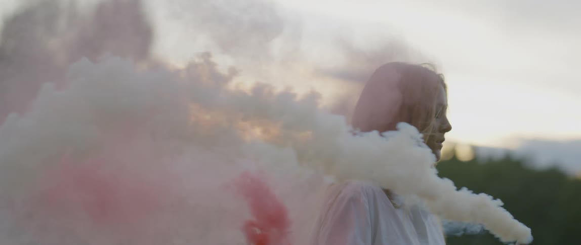 A woman holds smoke flares