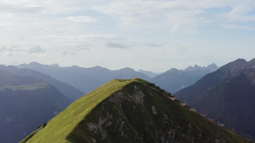 A cross can be seen atop a towering mountain with an array of solar panels installed this its peak