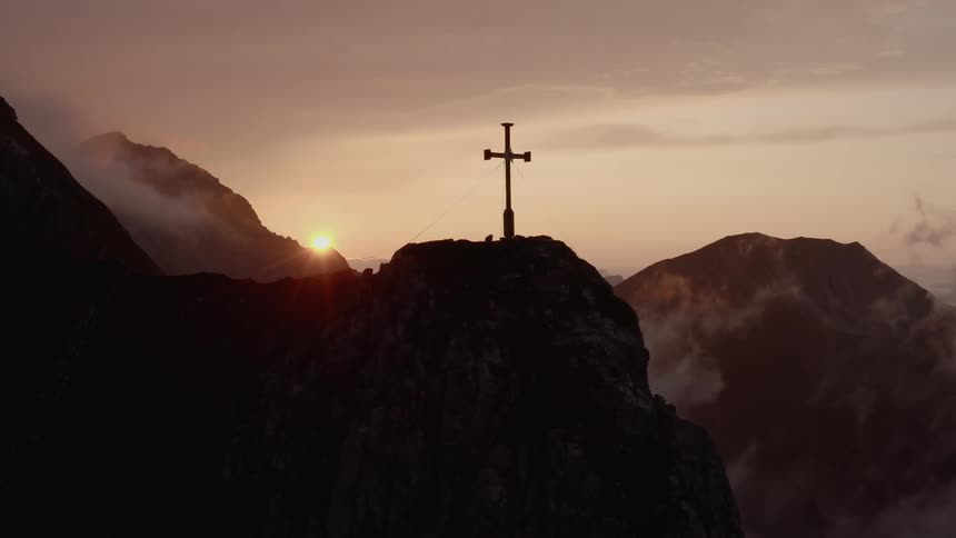 A cross sits at the top of a peak