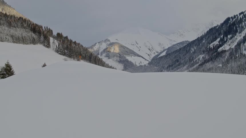 A snow covered hill in front of the mountains