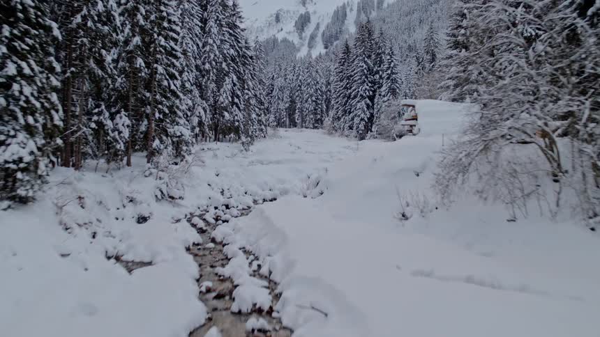 A narrow creek runs through snow covered ground