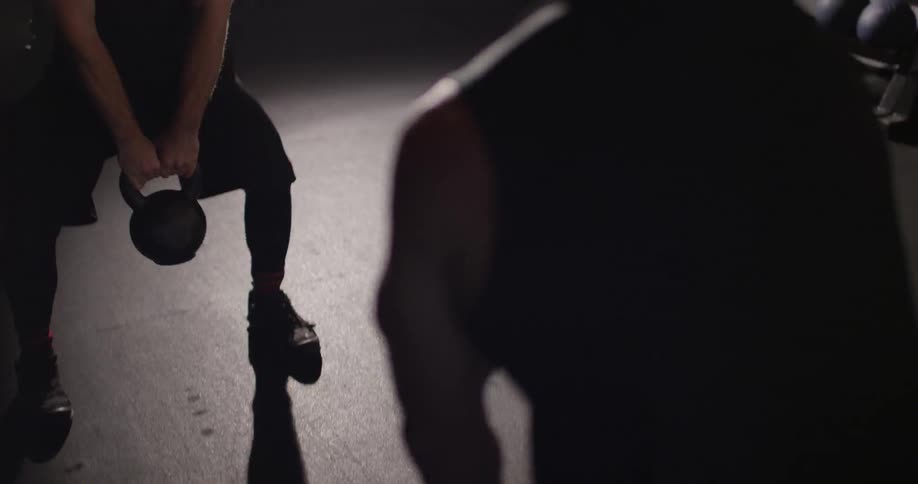 Two people are lifting kettlebells in a gym