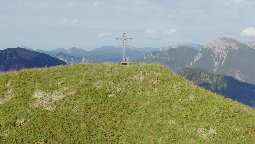 A cross on top of a hill with a neighborhood below