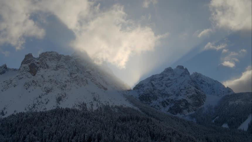 A forest covered with snow with mountains in the background