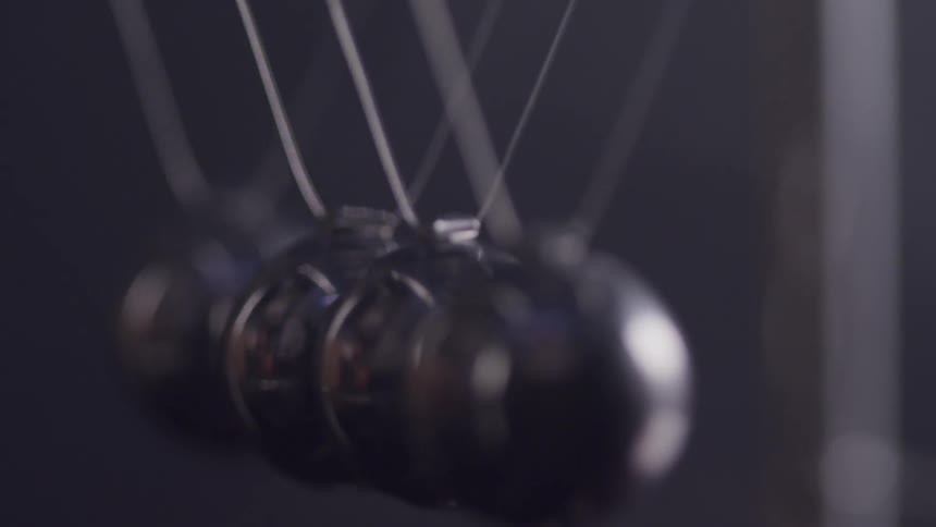 A row of shiny metal spheres are suspended with wires and the ones on each end swing back and forth and strike the others