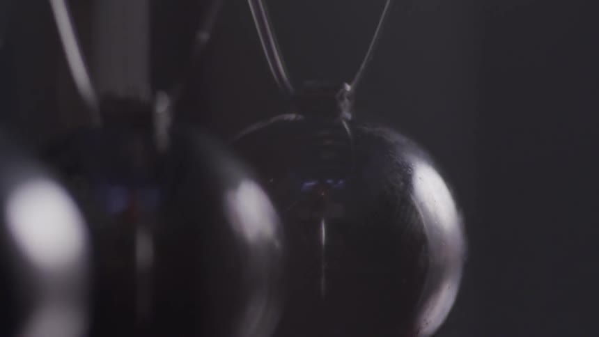 Close up of pendulum balls gently swinging back and forth