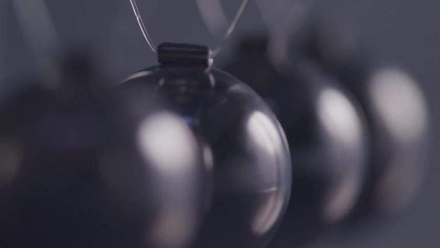 Metal balls in a newtons cradle swing and hit each other