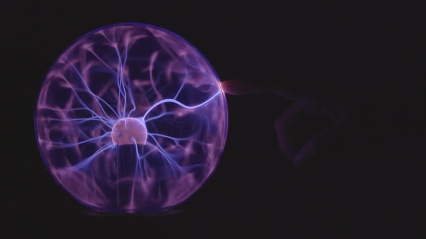 A plasma globe can be see discharging in a darkened room as a person touches the surface with their finger