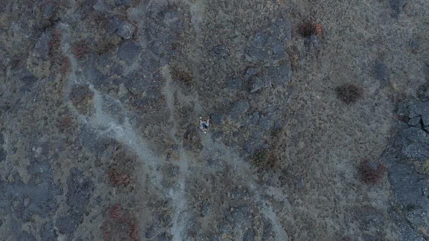 Person runs across rough terrain covered with scrub