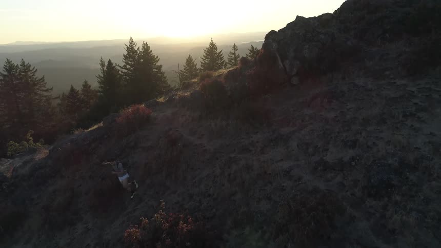 A man runs down a hill and almost falls