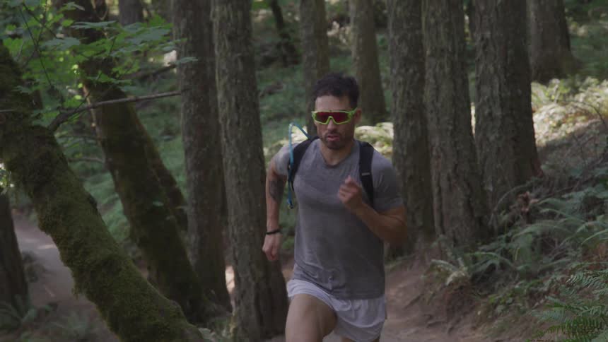 A man with black glasses running on the forest