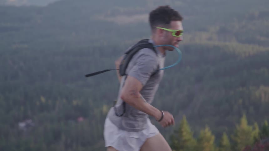 A male wearing shorts running outside near many trees