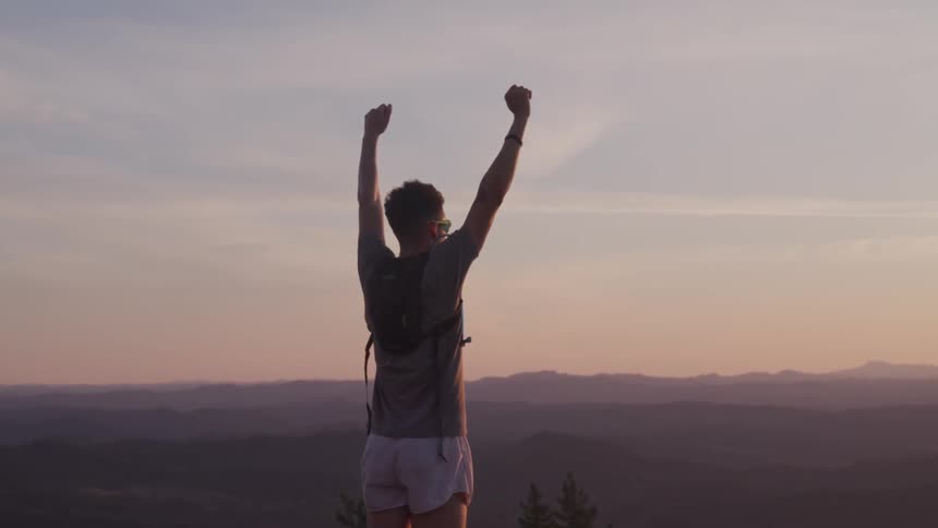 A person celebrating on top of the mountain
