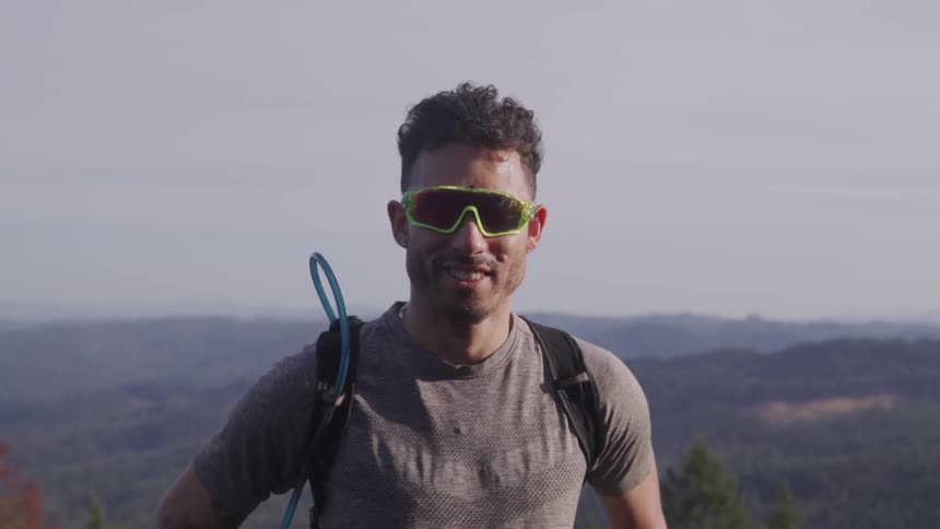A man stands on top of a hill overlooking a valley