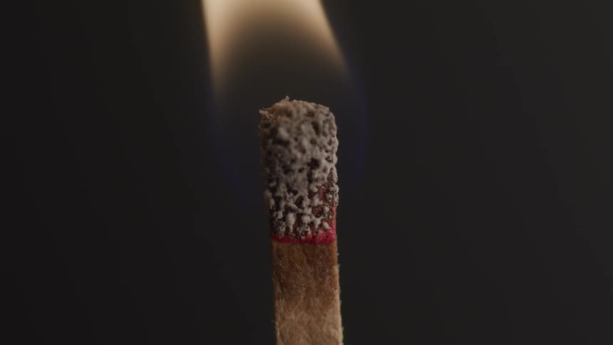 A matchstick burns against a dark backdrop