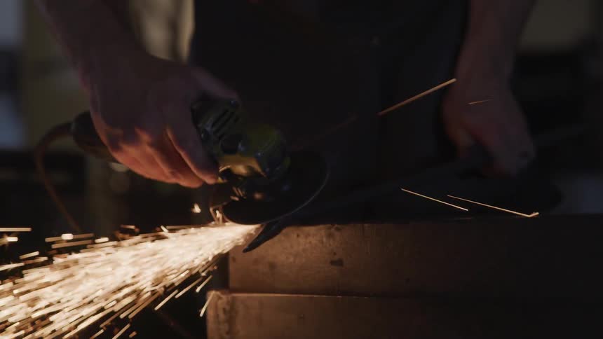 A machinist uses a grinding wheel on a piece of metal