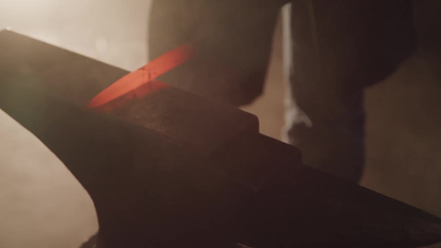 Person hammers glowing metal rod on anvil