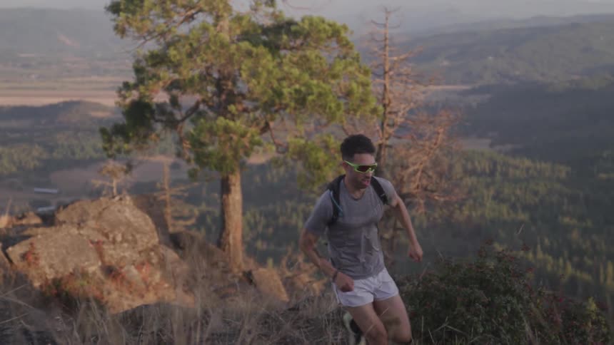 A man in running shorts jogs up a hillside