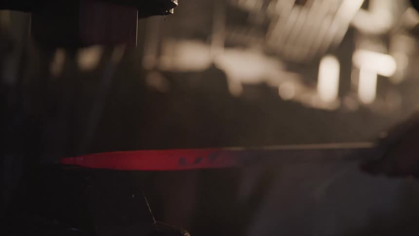 A hammer smacks against a hot metal iron