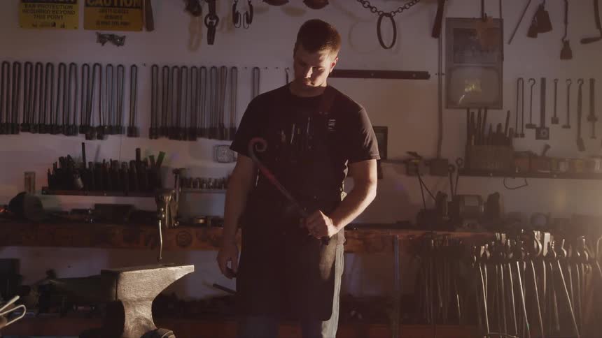 A man holds a piece of curved iron and stares at it