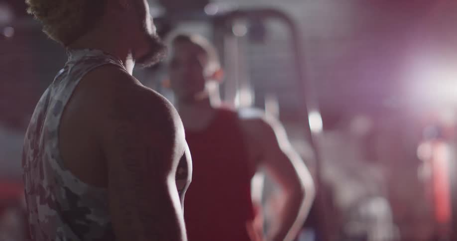 Man in a gym catches his breath and congratulates another man