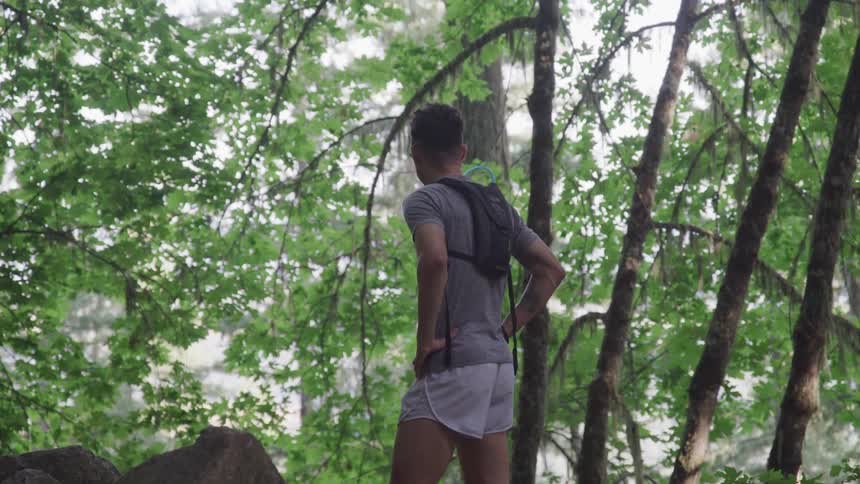 A man with his hands on his hips standing in the forest