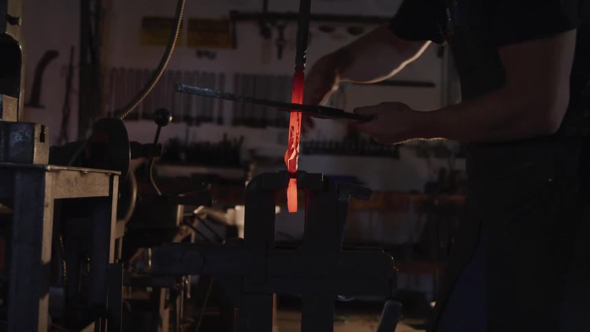 Man turns a lever that is holding a red hot object