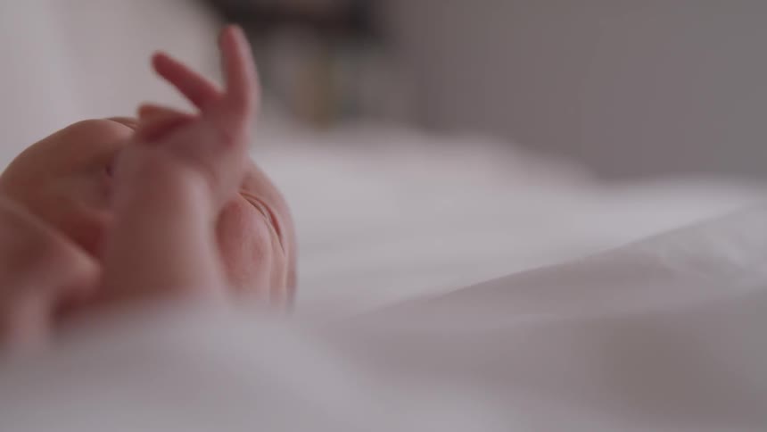 A newborn baby wriggles and smiles