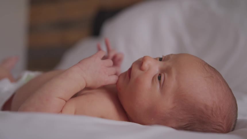 A newborn baby lies and looks up