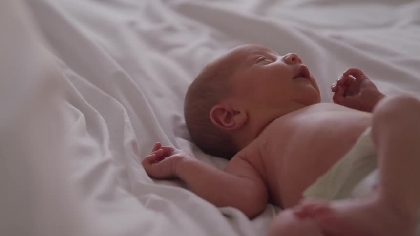 A newborn baby wriggles and smiles