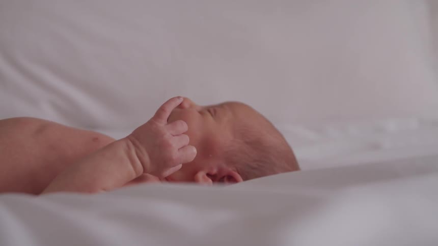 A newborn baby stretches and smiles