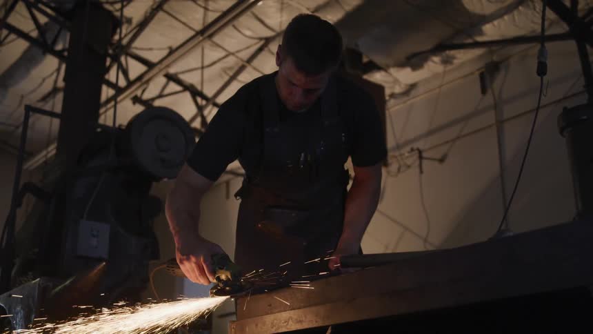Man polishes metal wedge in workshop
