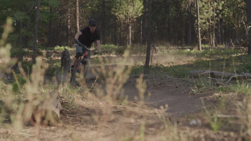Man rides a bike on the winding forest road in the woods