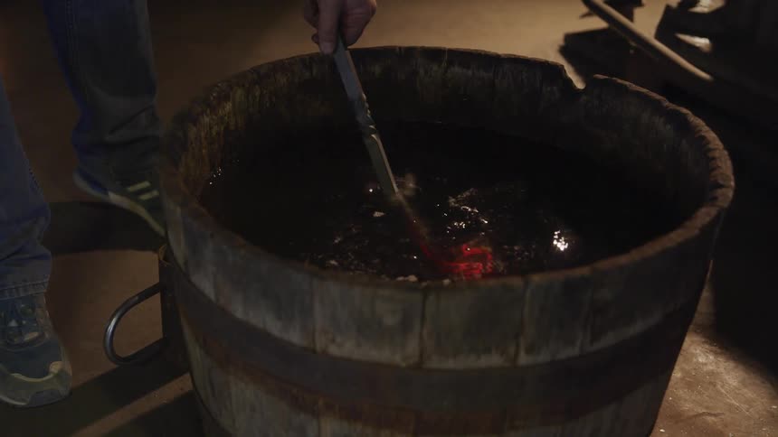 A man puts a hot iron in a bucket of water