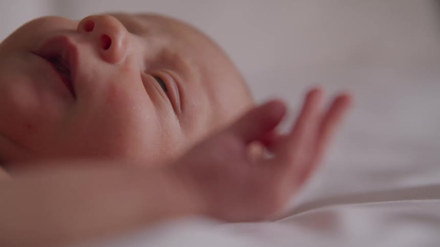 A newborn baby wriggles and smiles