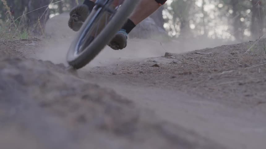 A young man rides his bike along a dirt path