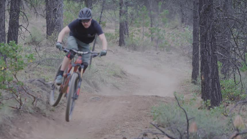 Man with mustache rides a bike and jumps over the forest track in the woods